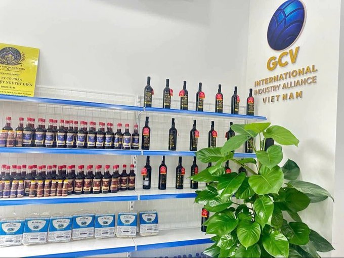 Shelves stocked with various bottles and automotive products in a display area, with a wall logo reading 'GCV INTERNATIONAL INDUSTRY ALLIANCE VIET NAM'.