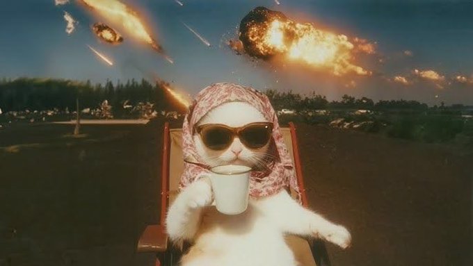 The image features a cat wearing sunglasses and holding a cup of coffee while sitting in a red chair. The background shows an explosion or fire, which adds intensity to the scene. The caption for this image reads "All projects on $BASE right now are solid entry zones for newcomers. And for those who aped in at higher levels— don't panic, just hold your bags. Think back to the original target." This message suggests that the cat's current project is a solid one and should be prioritized over others.