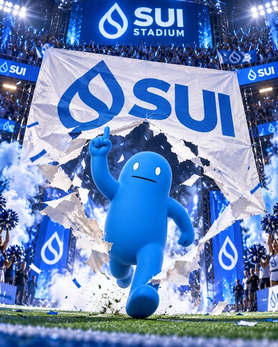 A blue, blob-like mascot bursts through a large white banner displaying the 'SUI' logo on a football field in a stadium setting.