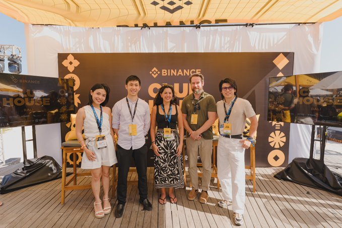 Five people pose for a photo at the Binance 'Crypto House Bali' event under a tent with wooden decking.