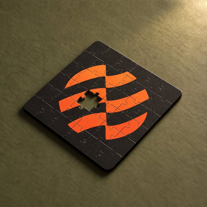 A black square jigsaw puzzle with an orange circular logo design featuring an arrow, with one puzzle piece missing from the center, resting on a textured olive-green surface.