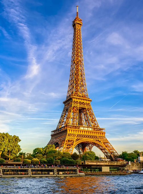 The Eiffel Tower stands prominently in Paris against a blue sky with wispy clouds, viewed from across the Seine River. The image relates to the post by symbolizing France, as Sequans, the French firm mentioned, has sold its entire Bitcoin position, including the last 63 BTC.