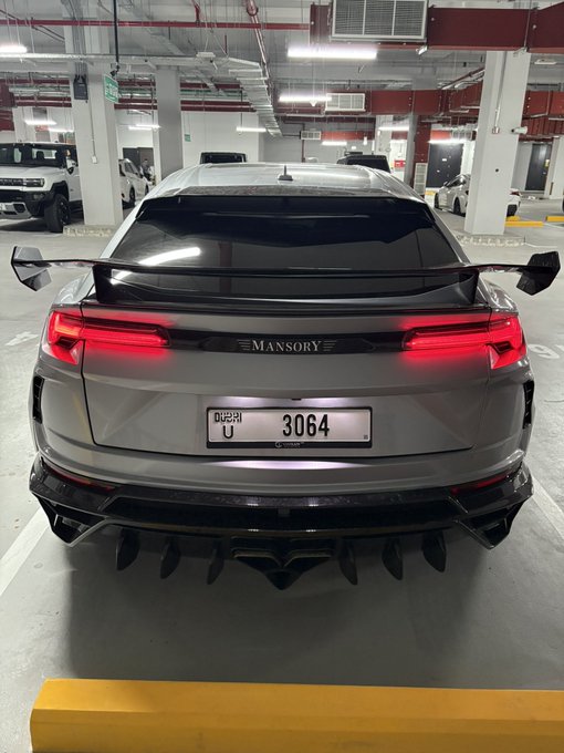 A gray Mansory-tuned sports car with an aggressive rear diffuser is parked in an indoor garage, displaying a Dubai license plate reading "U 3064." The prominent "MANSORY" badge and "GN" likely refer to the brand's custom modifications.