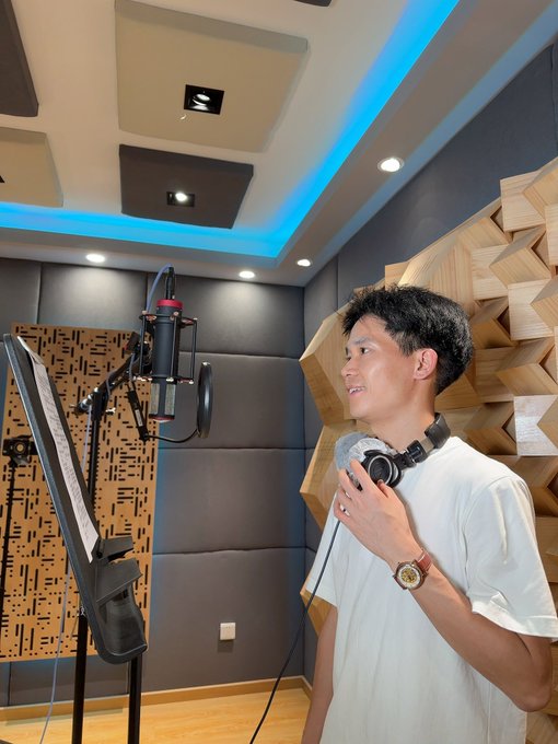 A man in a white shirt stands in a soundproof recording studio with acoustic paneling and a professional microphone, appearing to record content related to the post's promotion of becoming a financial KOL, professional trader, or leveraging AI quantitative trading tools.