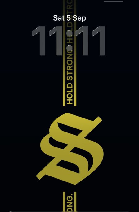 A mobile phone lock screen displaying 'Sat 5 Sep 11:11' with a black background featuring gold 'HOLD STRONG' tape and a stylized 'S' dollar sign logo.