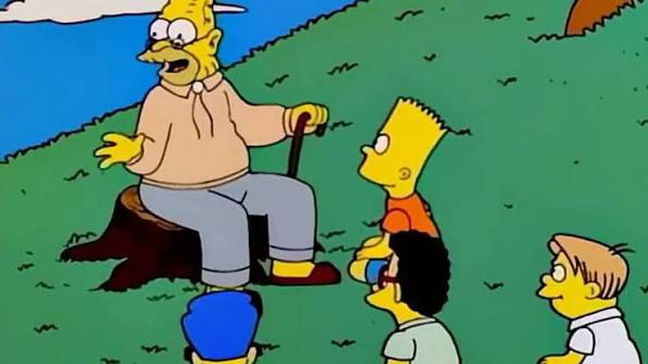 A scene from The Simpsons showing an elderly character with a cane sitting on a stump, talking to Bart Simpson and other children on a grassy hill.
