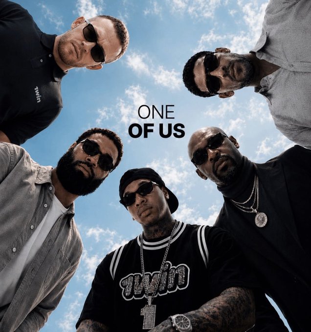 Five men wearing sunglasses look down at the camera against a blue sky, with the text 'ONE OF US' in the center.