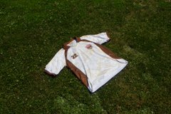A white and brown sports jersey lying crumpled on a grassy field.