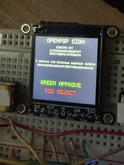 A small OLED screen on a breadboard displaying 'OPENPGP SIGN' with a signing key, an Ethereum address, and the text 'GREEN APPROVE' in green and 'RED REJECT' in red.