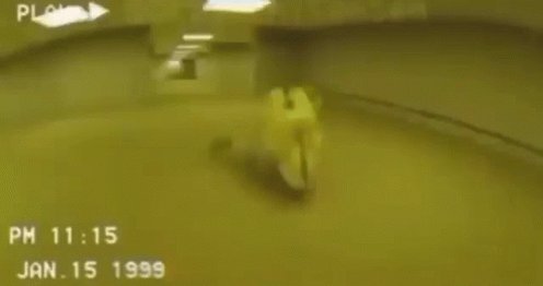 The image shows a person riding a motorcycle, captured from behind with the rider's body partially visible. The motorcycle appears to be moving at high speed as it races through an underground tunnel or racetrack. The surrounding area seems to be a parking lot or garage, and there is a clock in the background that reads "PM 11:15".