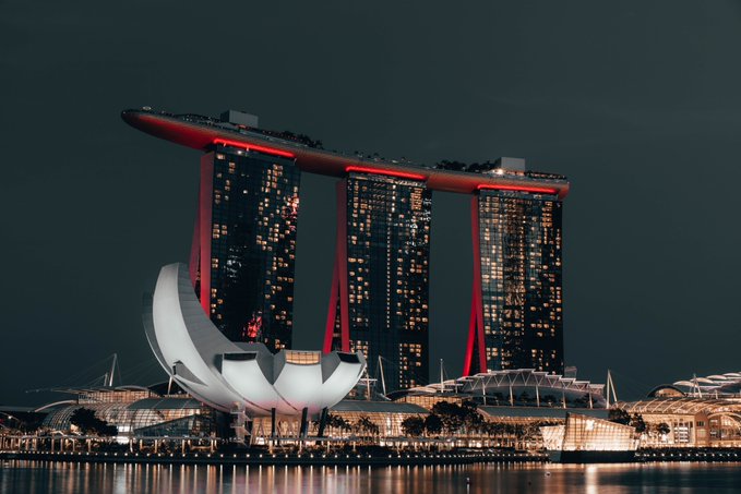 A nighttime view of the Marina Bay Sands hotel in Singapore with its three towers lit up and the ArtScience Museum shaped like a lotus flower in the foreground.