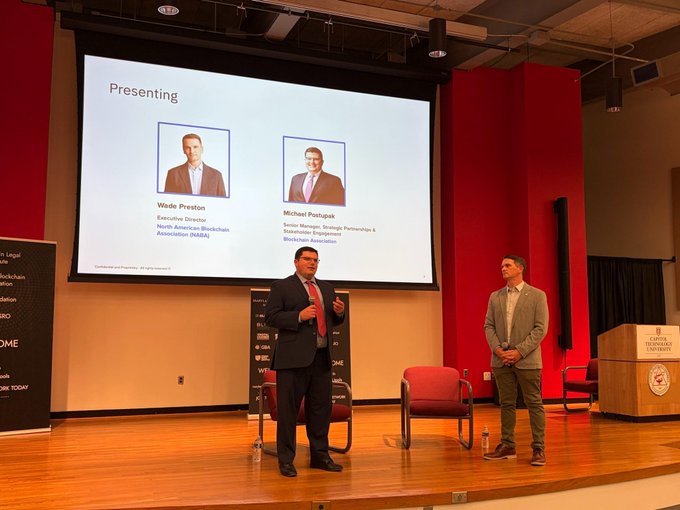Two men stand on stage at what appears to be an NAHB presentation, with a large screen behind them displaying their photos and titles: Wade Preston, Executive Director of the North American Blockchain Association (NABA), and Michael Pento of Pento Portfolio Strategies.