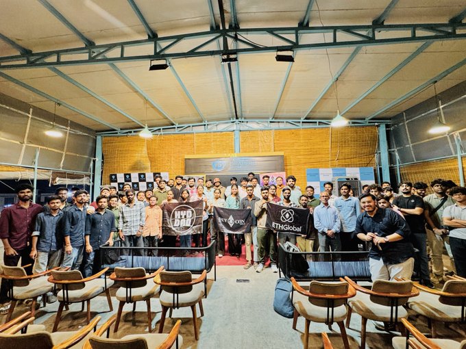 A large group of people pose together at an indoor event, with banners displaying 'BWD', 'Inco', and 'ETHGlobal' visible in the center.