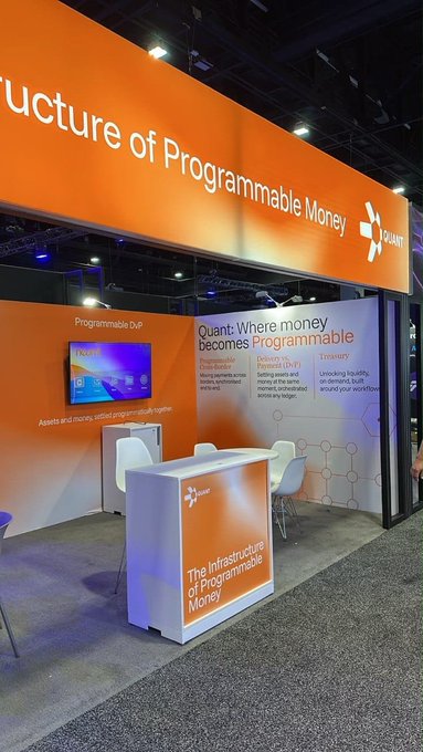 An orange-themed Quanti exhibition booth at a conference with signage reading 'Structure of Programmable Money' and 'Quanti: Where money becomes Programmable', describing Decentralized Distribution, Peerless DVPP, and Treasury services.