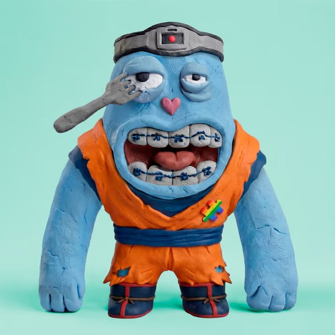 A claymation-style sculpture of a blue, brutish character wearing an orange gi with a dark blue belt and headband, featuring braces and a small heart on its nose.
