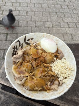 iced tea with a duck and egg on top, accompanied by rice and meat, sits on a wooden table.