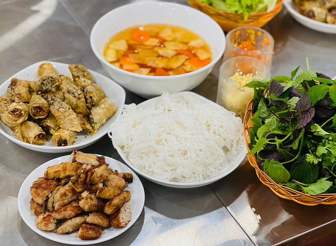 A spread of Vietnamese bún chả is laid out on a metal table, featuring grilled pork patties, fried spring rolls, a bowl of rice vermicelli noodles, a sweet-savory dipping broth with pickled vegetables, and a basket of fresh herbs and greens. The image pairs with the post's casual "bros" vibe to showcase a hearty homemade meal before returning to market trading, with the colorful dishes contrasting the tense, uptrend-driven mood of the caption.