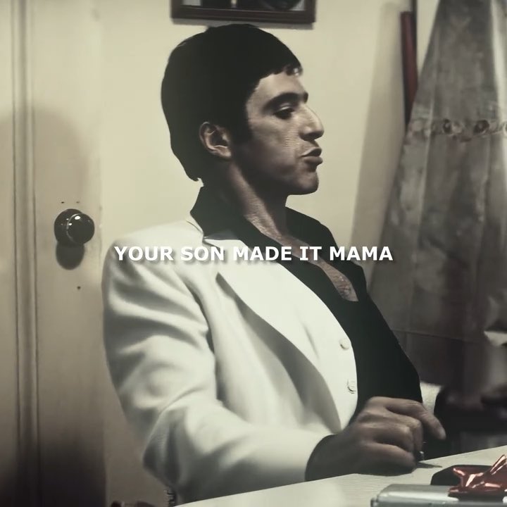 The image shows a still from a classic scene of a man in a white suit with a contemplative expression, overlaid with the text "YOUR SON MADE IT MAMA" — a famous line from Scarface. The caption references "$100 USD per Solana," humorously suggesting a milestone in Solana's price has finally been reached, likening the achievement to Tony Montana's triumphant declaration of success.