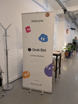 A welcome banner on a roll-up stand for the Grok Bot London Meetup hosted at SpaceX, featuring colorful speech bubble icons.