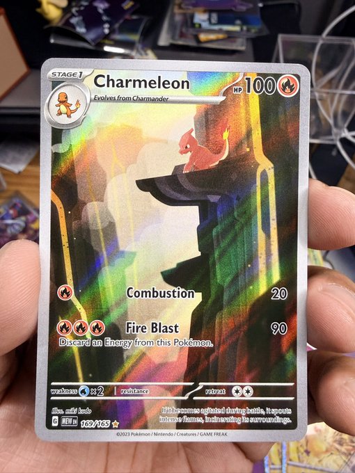 A hand holding a holographic 'Charmeleon' Pokemon trading card (163/165) from the 151 set, showing the Charizard evolution with attacks 'Combustion' and 'Fire Blast'.