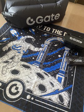 A space-themed tapestry featuring an astronaut and moon, branded with 'cGate' logos, laid out on a cutting mat alongside cGate branded merchandise.