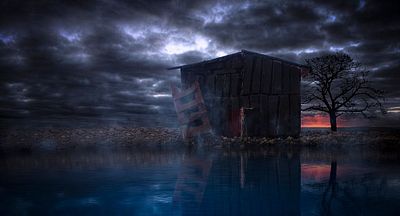 The image features a dark wooden cabin with a red door, situated next to a body of water under a cloudy sky. The cabin appears to be abandoned or neglected, adding an eerie atmosphere to the scene. The photo has been edited by @Armnabbasi and is part of their collection titled "Dark Cottage".