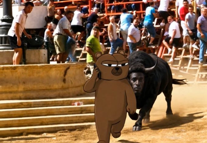 In a bullfighting arena with a crowd in the stands, a digitally added cartoon bear face covers the bull's head while a man's face is edited onto its body.