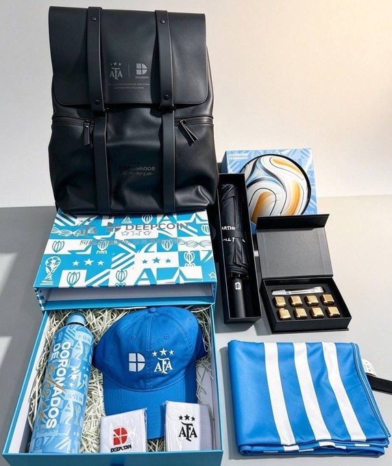 A promotional gift box containing a black DEEPCOIN backpack, a blue cap, water bottle, chocolates, an umbrella, and a striped blue pouch.