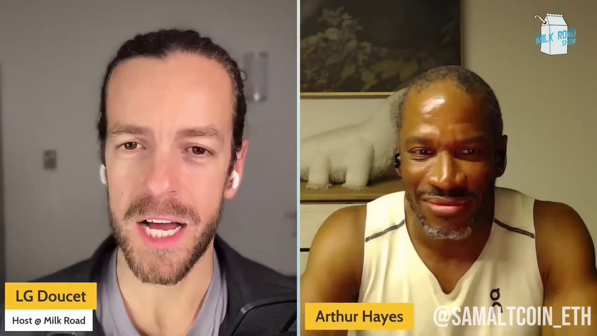 A man wearing a grey shirt is seen on one side of the screen smiling, while another man with a mustache wearing a white tank top appears to be frowning or looking serious during their video call conversation about the cryptocurrency market. The man in the middle is identified as Arthur Hayes and he is referred to as the "ETH killer" by another person in the image. Both men are sitting at a desk, surrounded by various items such as books and bottles.