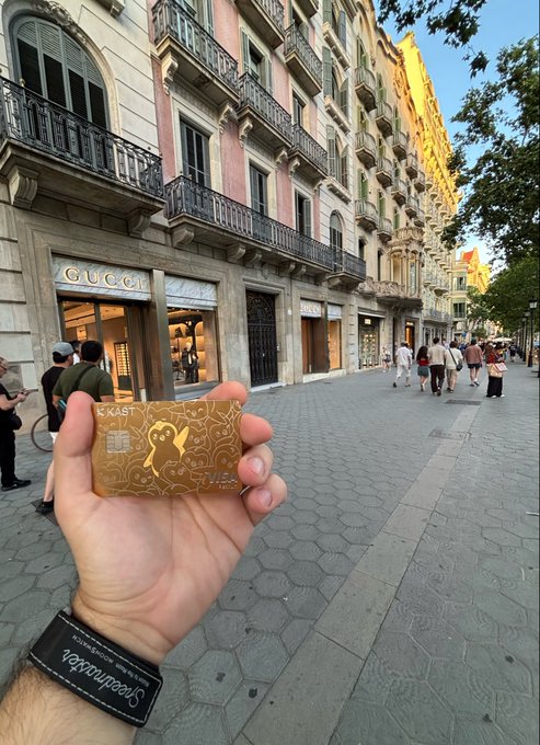 A person holding a gold 'Kiast' card on Barcelona's Passeig de Gràcia, with a Gucci storefront visible in the background.