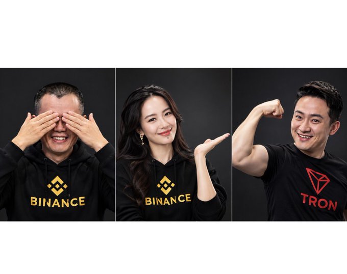 Three portrait photos against a dark background show a man covering his eyes and a woman gesturing, with two wearing "BINANCE" hoodies while the man on the right wears a "TRON" t-shirt and flexes his arm.