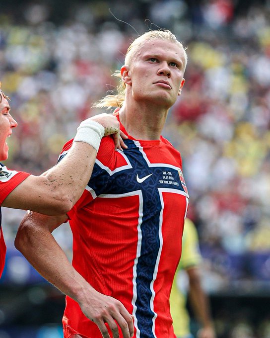 A blonde-haired Norwegian soccer player wearing a red jersey featuring the iconic blue and white Norwegian cross stands on the pitch, capturing the nation's World Cup hopes referenced in the tweet promising $15 to anyone who likes the post if Norway wins.