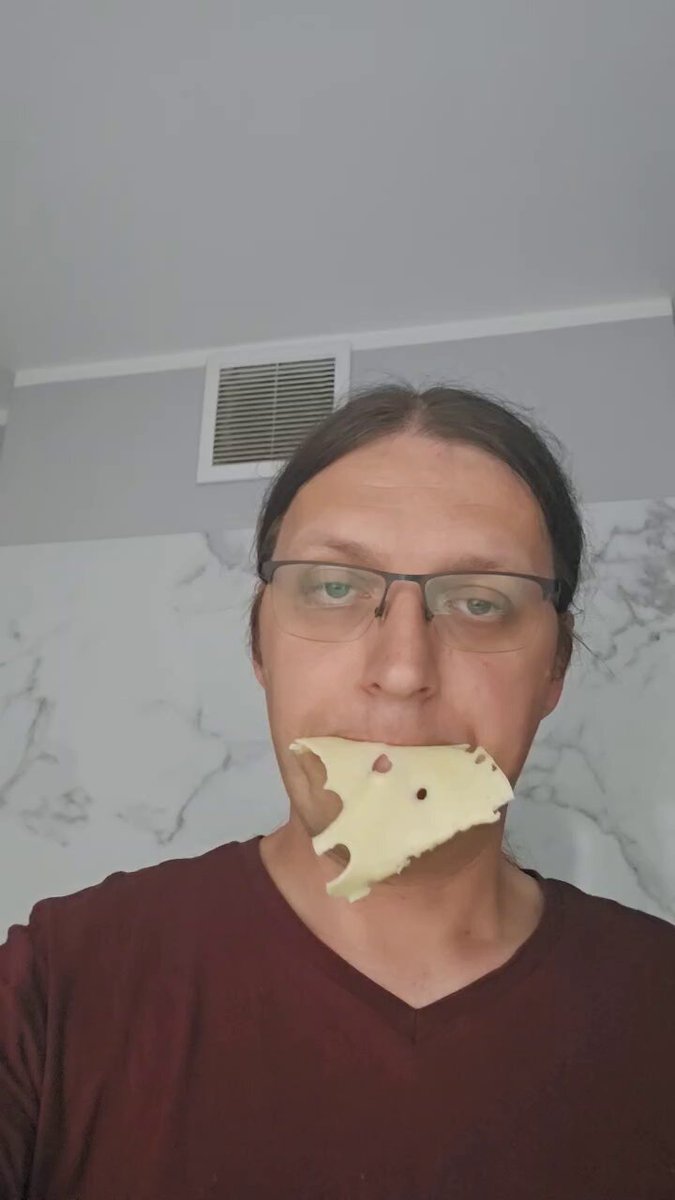 The image shows a man wearing glasses holding up a piece of cheese with his mouth while he takes a selfie. The caption below the picture suggests that they are spending quality time together, possibly during their child's online learning breaks or simply taking advantage of off-screen opportunities for work or leisure activities.