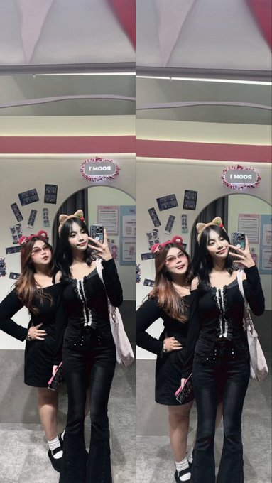 Two young women pose for mirror selfies in a black themed setting, both wearing matching black outfits with cat ears, with a sign reading "MOON!" visible in the background. The post in Indonesian roughly translates to "met me HAHA omg she's really pretty and so tall, my sister, the tall one is her," suggesting a casual fan encounter with her sibling.