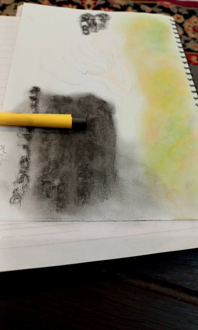 An open sketchbook page with a pencil charcoal drawing in progress and a yellow marker, showing abstract dark and colorful washes on lined paper.