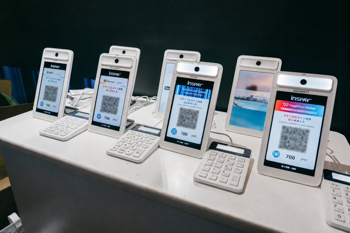 A row of white InsPay cryptocurrency wallet kiosk devices displayed on a counter, each showing a QR code and '700 USDT' on the screen.