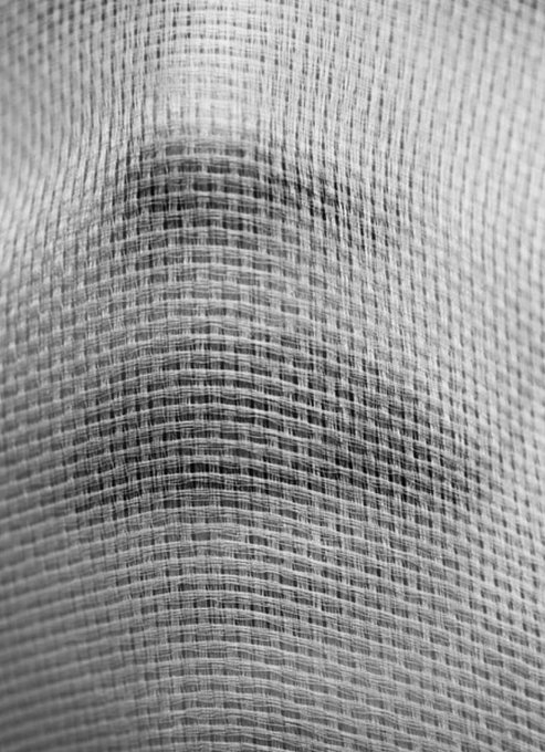 A close-up macro photograph of a gray, textured woven fabric displaying a fine grid-like pattern.