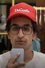 A man wearing a red "Degods" cap and glasses holds a phone, representing the FrankDeGods community referenced in the post about Trader Solstice's $STONK position being up $5.28M. The image visually anchors the DeGods/NFT branding tied to the trader's bullish thesis.