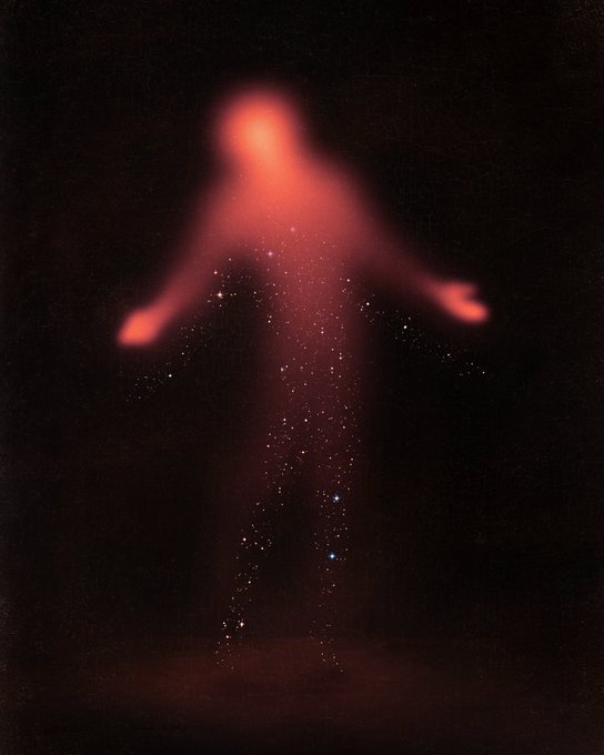 An artistic image showing a glowing, blurred reddish humanoid figure standing against a black background, surrounded by sparkling particles and a faint constellation overlay.