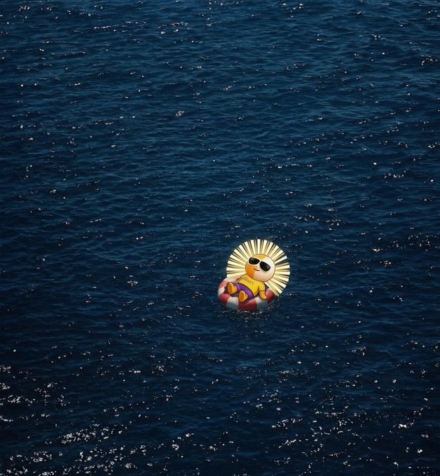 An inflatable sun pool float with sunglasses floats alone in the deep blue ocean.