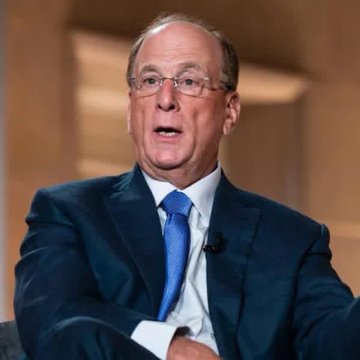 The image shows an older man wearing glasses and a blue suit jacket sitting down, possibly during a talk show event or news segment. The focus of his attire seems to be business or professional rather than casual. However, he also has an interesting accessory - a tie with a blue pattern on it. This tie adds a touch of personality or style to the otherwise formal setting and might even spark conversation among the viewers about the subject matter being discussed.