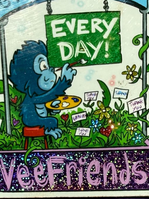 Artwork for the 'VeeFriends' collection featuring a blue furry creature painting an 'EVERY DAY!' sign on a green canvas, with small signs reading 'THANK YOU' and 'GRACIAS' in the grass below, with 'VeeFriends' written in stylized text at the bottom.