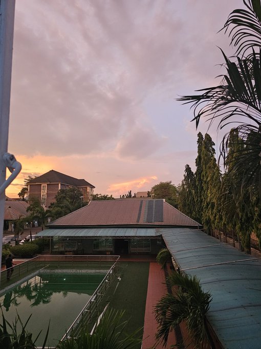 The image shows a view of an outdoor swimming pool area with a house, palm trees, and a building across from the pool. The sky above has a pinkish hue, suggesting that the photo was taken during sunset or sunrise. The text "Good night Ct Study @TheARCTERMINAL" is present in the image as well.