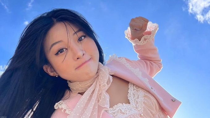 A young woman poses confidently against a bright blue sky, wearing a pink polka-dot blouse with delicate lace cuffs and her fist raised triumphantly. The image conveys a determined, "punch up" attitude that mirrors the post's mocking tone toward investors who keep waiting for a dip before buying HYPE, suggesting they'll likely miss the rally instead.