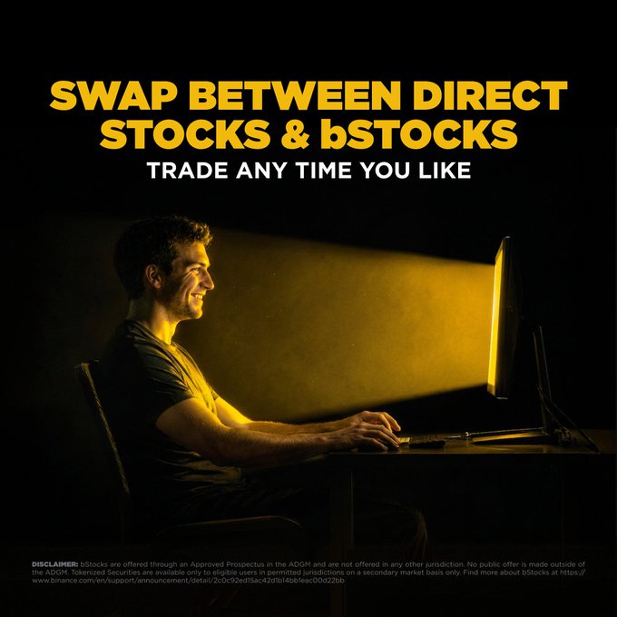 A man smiles at a computer screen illuminated in yellow light, sitting in an otherwise dark room. The image features the bold text "SWAP BETWEEN DIRECT STOCKS & bSTOCKS - TRADE ANY TIME YOU LIKE," reinforcing the post's message about the flexibility of moving between direct stocks and bStocks, with a disclaimer at the bottom about bStocks being offered through an Approved Prospectus in the ADGM.