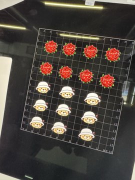 A computer monitor displays a digital grid with stickers of red roses and cowboy-hat-wearing cats arranged in rows.