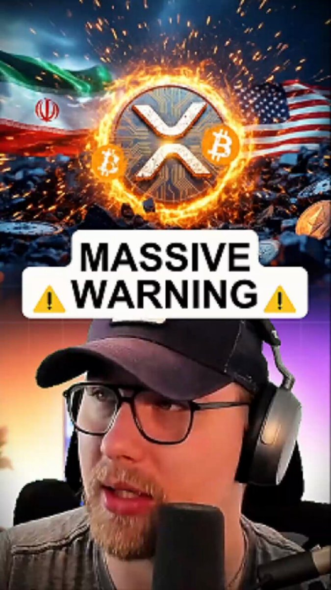 The image features a man wearing glasses, sitting behind a microphone with headphones on his head. He appears to be talking into the microphone or recording a video. The background of the image shows an American flag along with a Bitcoin logo and a warning sign that reads "MASSIVE WARNING". The caption below the image states "BREAKING: TRUMP JUST NUKED !!! HERE'S WHY!".