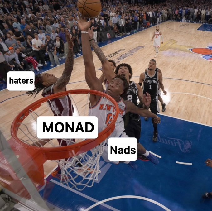 The image shows a basketball player from the New York City Bulls jumping up to take a shot at the basket, with his teammates attempting to block him. A basketball hoop can be seen prominently in the scene. The text "Monad" appears multiple times throughout the image, possibly indicating that this is related to Monad's basketball team or their performance on the court.