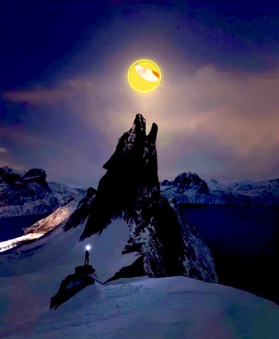 A lone figure with a glowing lantern stands atop a jagged, snowy mountain peak beneath a brilliant yellow moon, symbolizing the LUNC community standing ready at a pivotal breakout point as crypto market momentum builds. The solitary climber's light represents the dedicated core community illuminating the path forward toward the next bullish wave.