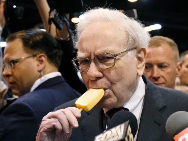 Warren Buffett is seen biting into a Dairy Queen ice cream bar while being interviewed, with a "FOX" microphone visible. The image ties into the caption by capturing the legendary investor in one of his iconic moments, reflecting on his decades-long run as Berkshire Hathaway's Chairman.